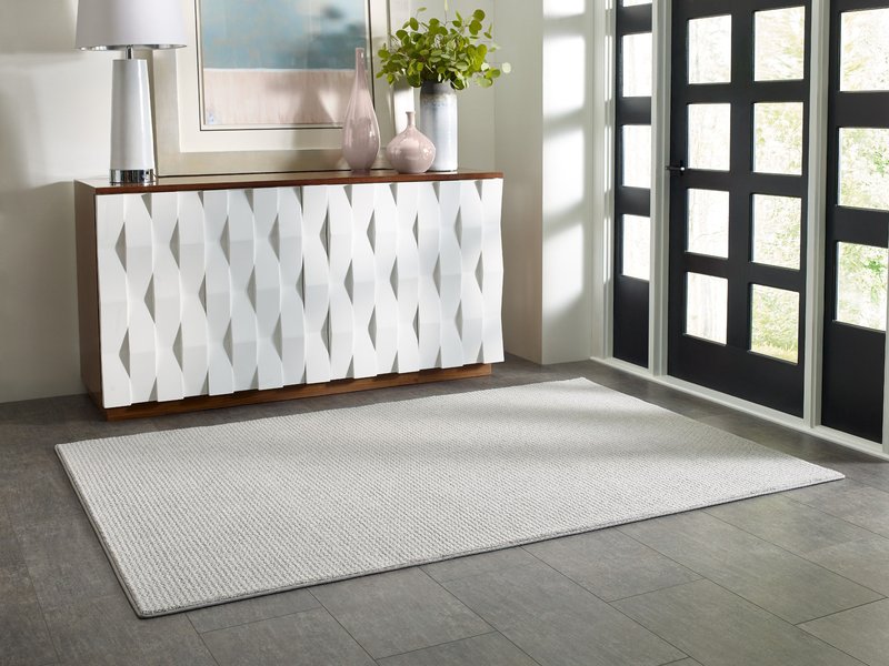 wood entry cabinet with white cabinet doors in front of white area rug on grey floors - Carpet Plus Flooring LLC