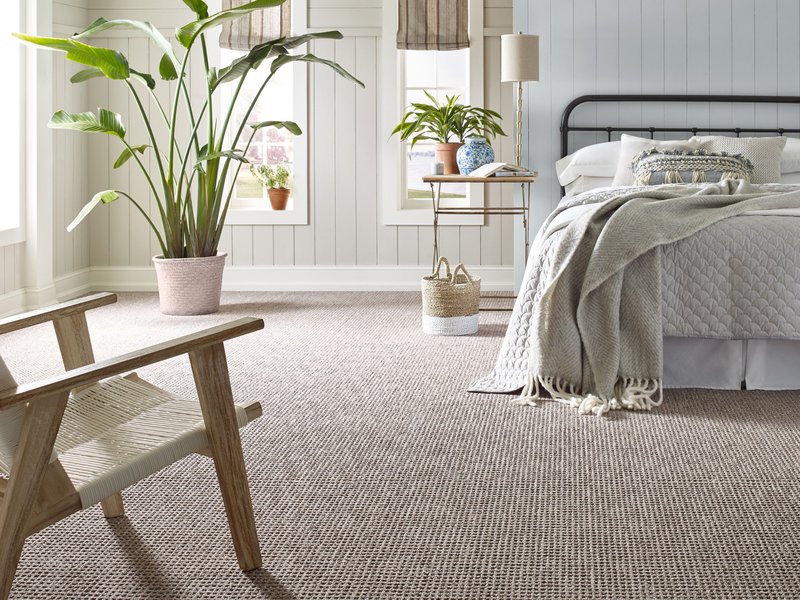 bedroom with wood chair, indoor plant, bed, and carpet - Carpet Plus Flooring LLC