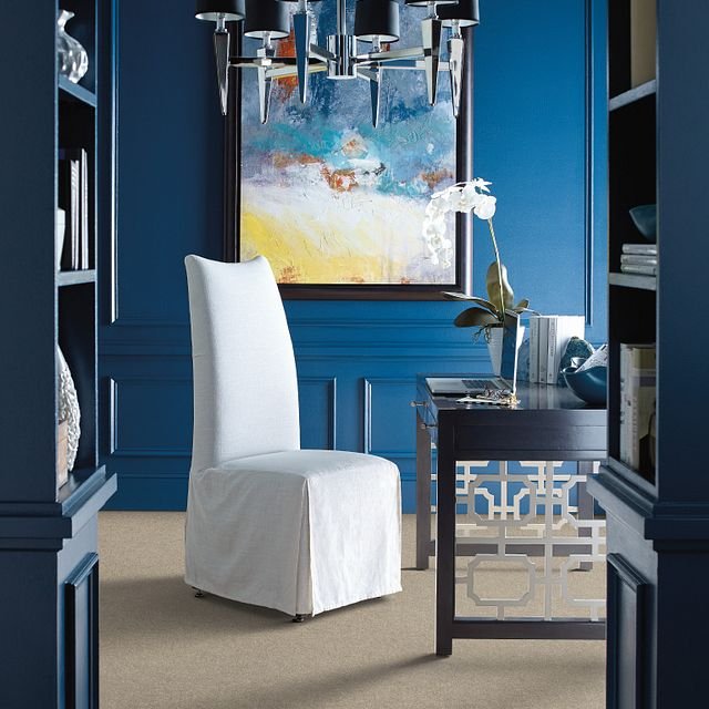 white covered chair in room with blue walls and colorful painting - Carpet Plus Flooring LLC